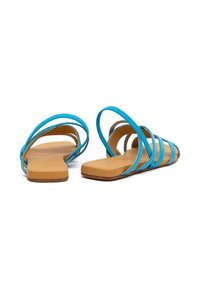 Blaue Sandalen mit flachen Sohlen und mehreren dünnen Riemen sowie einem glatten, hellbraunen Fußbett. Ohne Absatz, minimalistisches Design.