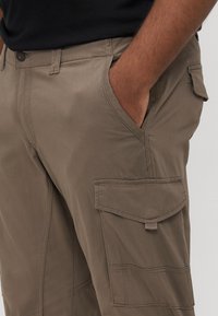 Χακί παντελόνια cargo από μαλακό ύφασμα, με πλαϊνές τσέπες, εφαρμοστό μέση και ενισχυμένες ραφές κατά μήκος των ραφών για ανθεκτικότητα.