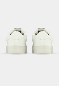 Λευκά δερμάτινα αθλητικά παπούτσια με λεία επιφάνεια, στρογγυλεμένη μύτη, επενδεδυμένο κολάρο και μινιμαλιστικό σχέδιο με επίπεδη σόλα.