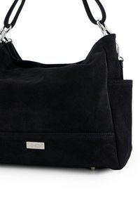 Czarna zamszowa torebka o miękkiej fakturze, ze srebrnym okuciem i tabliczką z logo. Posiada przestronne wnętrze oraz płaską podstawę z metalowymi stopkami.