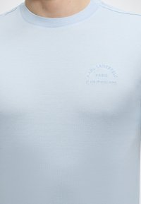 Φωτεινό γαλάζιο μπλουζάκι με στρογγυλή λαιμόκοψη και λεπτή ανάγλυφη επιγραφή "KARL LAGERFELD PARIS 21 RUE ST-GUILLAUME" στο στήθος.