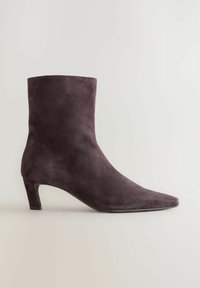 Tumedast lillast nubukist ankle-boot, millel on terav nina ja keskmise kõrgusega plokk-kand. Sile tekstuur ja minimalistlik disain.