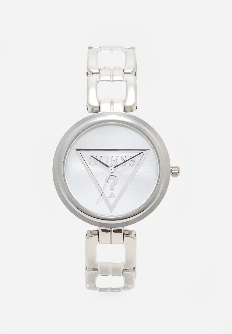 Montre en métal argenté avec boîtier rond et bracelet à motifs. Le cadran présente un logo triangulaire avec "GUESS" et un point d'interrogation au centre.