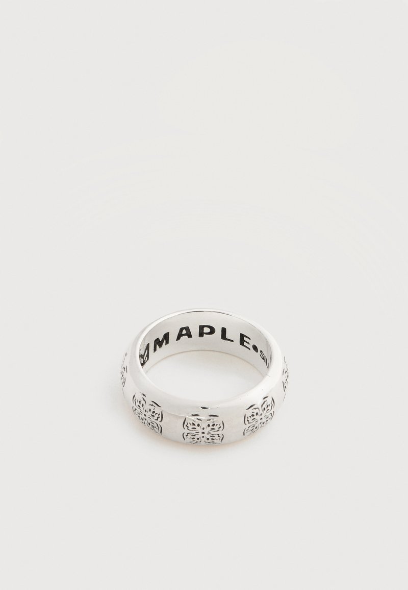 Bague à anneau en argent avec motifs floraux gravés en noir et texte « MAPLE » visible à l'intérieur de l'anneau, présentée sur un fond blanc uni.