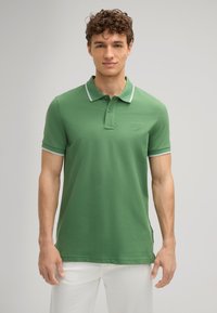 Grünes Poloshirt mit weißen Akzenten am Kragen und an den Ärmeln, gefertigt aus einem glatten Stoff. Verfügt über ein dezentes Logo auf der Brust.