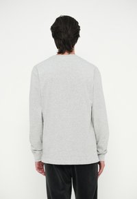 Graues Langarm-T-Shirt mit Rundhalsausschnitt und lockerer Passform. Der Stoff wirkt weich, mit minimalen Nähten und ohne sichtbare Logos.