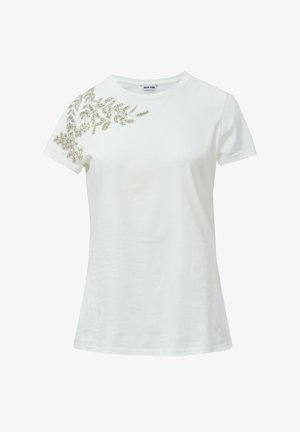 Camiseta de algodón blanca con mangas cortas, que presenta un diseño decorativo de hojas de cuentas plateadas en el hombro izquierdo. Cuello redondo clásico.
