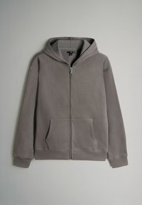 Pelēks kapuces džemperis ar priekšējo kabatu, regulējamu kapuci, ribota apkakle un gluda tekstūra. Iezīmējas ar smalkiem šuvju detaļām.