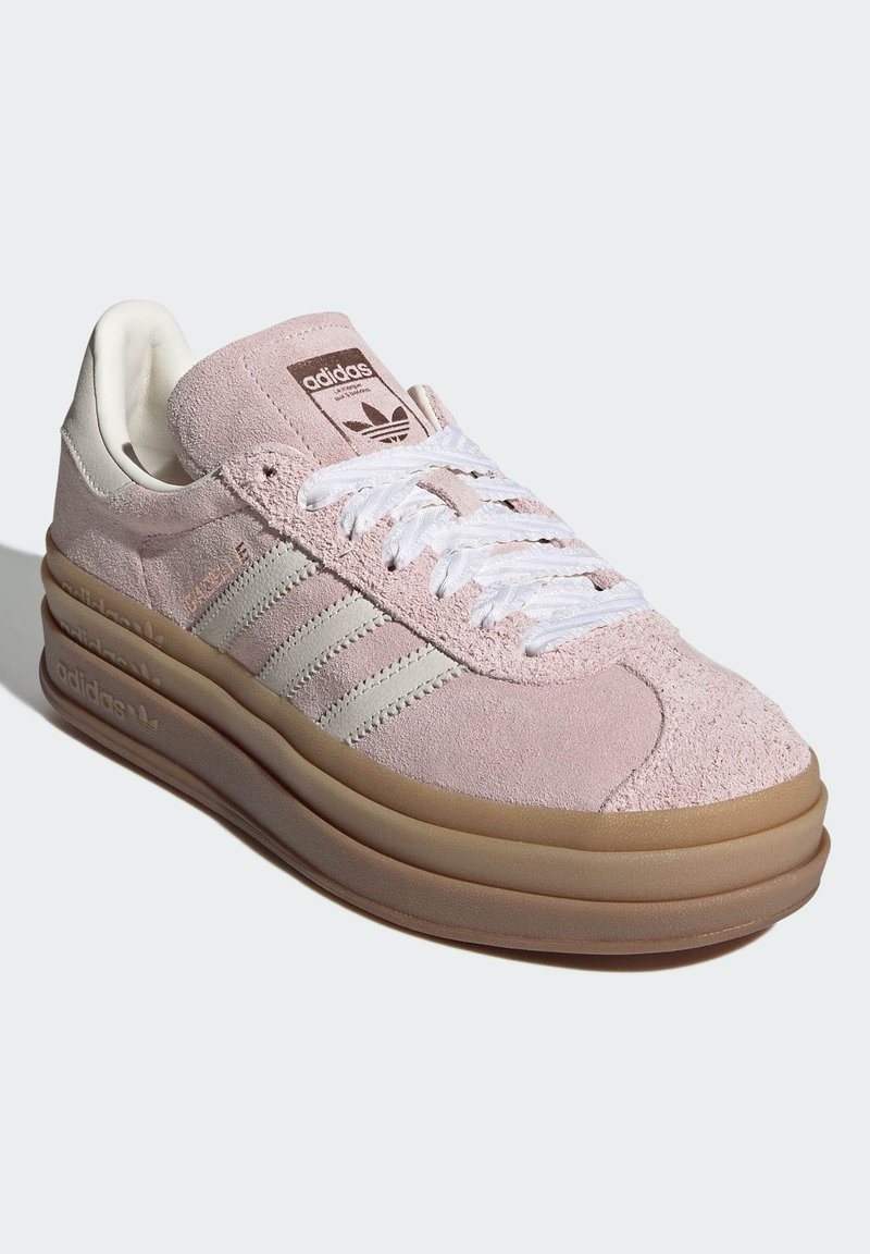 Lichtroze suède sneaker met witte leren strepen en veters. Voorzien van een afgeronde neus en een dikke, bruine rubberen zool. Adidas-logo op de tong.