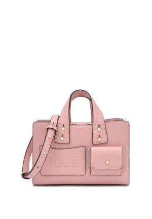 Bolso estructurado rosa con dos asas superiores, una correa larga para el hombro, bolsillos delanteros y herrajes dorados. El bolsillo delantero lleva TOUS en relieve.