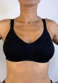 Sujetador negro con una tela suave y elástica. Presenta un escote en V, detalles florales en las tirantes y costuras para soporte.