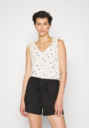 Top de tiras ligadas em flores creme, combinado com calções texturizados pretos de cintura alta com fecho frontal em laço.