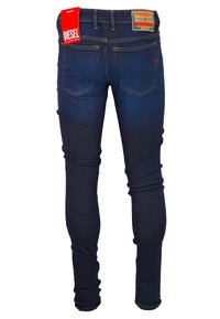 Jeans Diesel slim-fit bleu foncé vus de l'arrière, avec des étiquettes rouges et brunes marquées sur la ceinture.