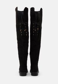 Fekete, térd fölé érő, suede csizmák, fűzős elöl kialakítással, arany hardware-rel, lapos gumitalppal és sima, texturált felülettel.