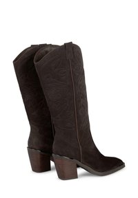 Stivali da cowboy in suede marrone scuro con cuciture decorative, una punta leggermente appuntita e un tacco in legno chunky. Texture morbida e design alto.