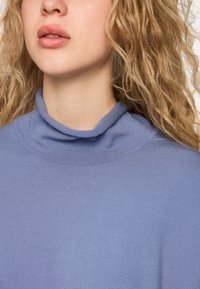 Hellblaues Rollkragensweatshirt mit glatter Textur und tailliertem Design. Verfügt über einen umgeschlagenen Kragen und nahtlose Schultern.