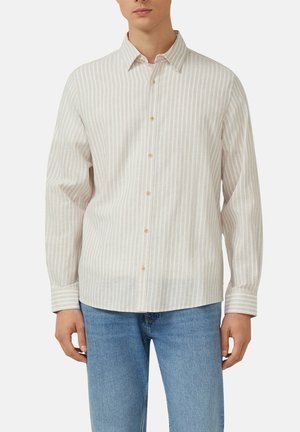 Mann, der ein beige-weiß vertikal gestreiftes Hemd mit Knöpfen und langen Ärmeln sowie blaue Jeans aus Denim trägt.