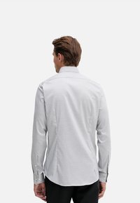 Camicia grigio chiaro con bottoni, motivo testurizzato, maniche lunghe e colletto classico. Presenta polsini con bottoni e una vestibilità sagomata.