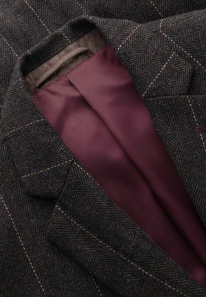 Dunkelgrauer Blazer mit Fischgrätenmuster, hellen Steppnähten und sichtbarem, glattem, tief bordeauxrotem Innenfutter.