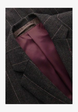 Dunkelgrauer Blazer mit Fischgrätenmuster, hellen Steppnähten und sichtbarem, glattem, tief bordeauxrotem Innenfutter.
