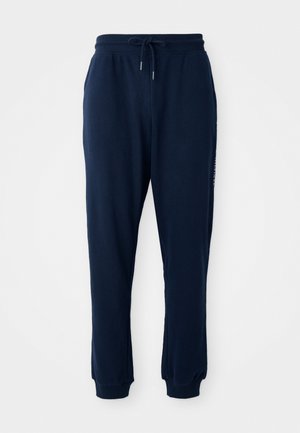 Námornícky modré tepláky vyrobené z mäkkého zmesového bavlneného materiálu, s elastickým pásom a šnúrkou na stiahnutie, a s manžetami na kotníkoch. Nielen logo ako decentný detail.