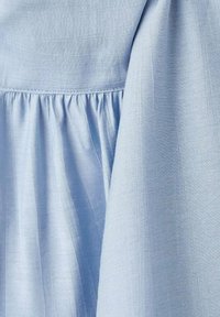 Tela azul clara con una textura suave, que presenta pliegues recogidos a lo largo de la costura y un brillo sutil. El material parece ligero y etéreo.