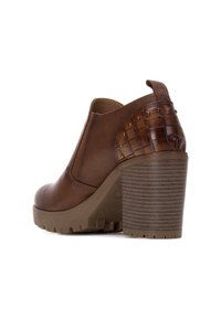 Botín marrón hasta el tobillo con una parte superior de cuero liso, acento de estampado de cocodrilo texturizado y un tacón robusto con estrías. Cuenta con una tirador y paneles laterales elásticos.