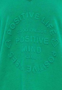 Grüner Baumwollpullover mit geprägtem Text: „POSITIVE LIFE“, „GOOD ENERGY“ und „POSITIVE MIND CLUB“, verziert mit Herz-Akzenten.