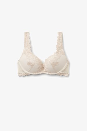 Beige kanten bh met bloemmotieven, gevoerde cups en brede bandjes, plat gelegd op een witte achtergrond.