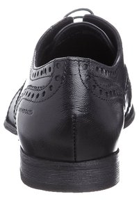 Svarta läderskor med slät yta, rund tå, dekorativa perforeringar och en låg gummihäl.