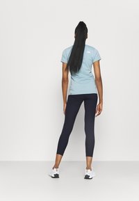 Camisa de manga corta azul claro y leggings navys oscuros, ambos hechos de tela elástica. Zapatillas blancas completan el atuendo atlético.
