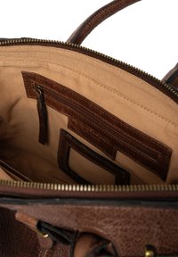 L'interno della borsa a tracolla in pelle marrone presenta una fodera in tessuto beige, una tasca con zip e diverse fessure per l'organizzazione. Dettagli con zip in tonalità oro.