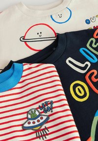 Trei hanorace: unul crem cu grafică a planetelor, unul bleumarin cu litere colorate și unul cu dungi roșii, având un OZN și broderie cu "HAIDE!".