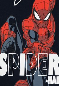 Rood en zwart Spider-Man graphic op marineblauwe stof, met gedetailleerde webpatronen en vet witte tekst die "SPIDER-MAN" spelt.