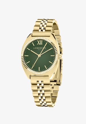 Guldtonet ur med grøn skive, romersk tal XII, minimalistiske time-markører og et glat metalarmbånd med et sammenkoblet design.
