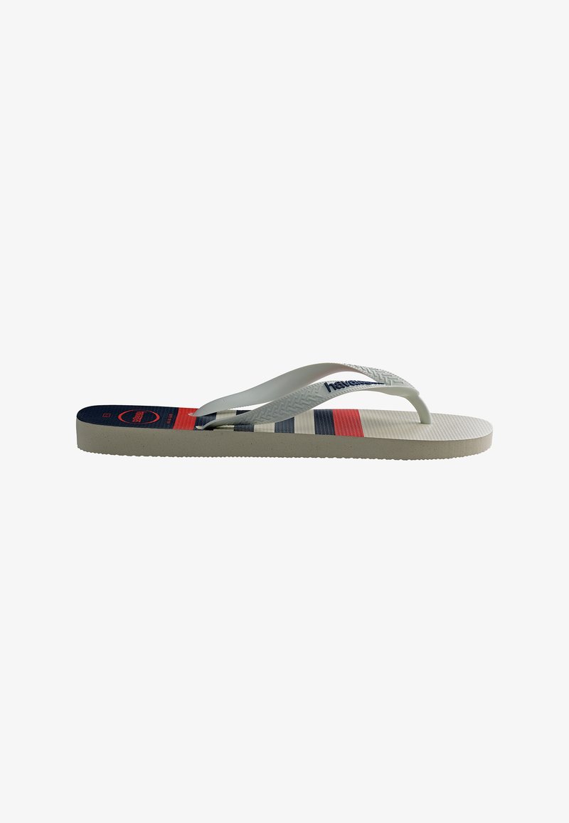 Tongs blanches avec des brides texturées et des rayures horizontales bleues, rouges et grises sur la semelle, vues de côté.