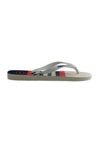 Tongs blanches avec des brides texturées et des rayures horizontales bleues, rouges et grises sur la semelle, vues de côté.