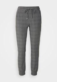 Grå avsmalnande joggerbyxor med elastiska muddar, dragsko i midjan, dragkedjefickor på sidan och ljusa sidosträck, visade på vit bakgrund.