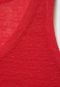 Red knit tank top featuring a ribbed neckline and slightly textured fabric. The stitching is visible along the edges.