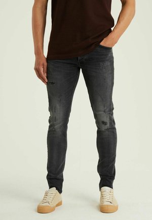 Jeans neri slim-fit, sbiancati con dettagli logorati e leggera sfumatura. Abbinati a sneaker beige con lacci texturizzati e suole in gomma.