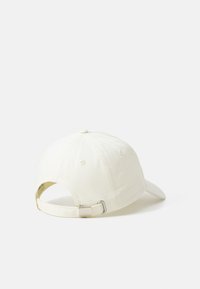 Boné de beisebol branco em algodão com aba curvada, tira ajustável na parte de trás e seis furos de ventilação na parte superior.