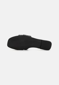 Talpa neagră de pantof cu un finisaj neted, având un toc ușor ridicat și un model texturat pentru aderență. Design simplu și funcțional.