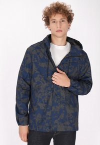 Giacca blu navy con un motivo esagonale e dettagli grigi. Presenta un cappuccio, tasche anteriori e una chiusura con zip. Tessuto liscio.