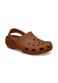 Sabot en plastique marron avec des trous de ventilation, une sangle arrière et une semelle texturée. Présente un bouton logo sur le côté.