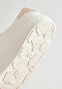 Baskets de couleur claire avec une semelle blanche texturée. Le dessous présente divers motifs ludiques, y compris des cornets de crème glacée et des pizzas.