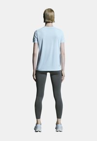 Ljusblå kortärmad träningsskjorta med rund halsringning, matchad med grå leggings och vita träningsskor. Slät tygstruktur.