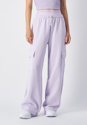Lichtpaarse cargobroek van zachte stof, met twee zijzakken, een elastische tailleband en een relaxte fit. Witte sneakers maken de look af.