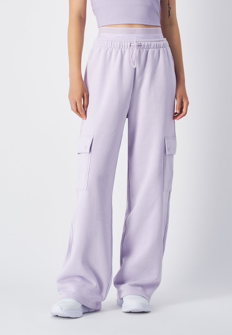 Lichtpaarse cargobroek van zachte stof, met twee zijzakken, een elastische tailleband en een relaxte fit. Witte sneakers maken de look af.