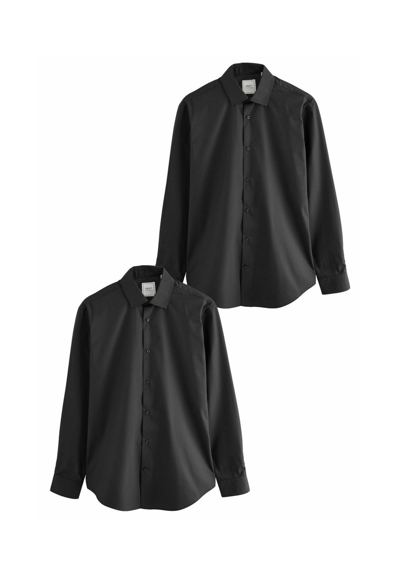 Chemises noires à manches longues, fabriquées dans un tissu doux, avec un col standard, une fermeture à boutons et un ourlet arrondi. Deux chemises sont exposées.