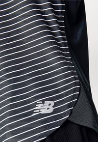 Black athletic fabric with white horizontal stripes and an "NB" logo in silver on the lower right corner. Smooth texture, sporty design.